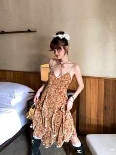 Woman in a polka dot spaghetti strap dress with an updo in a bedroom