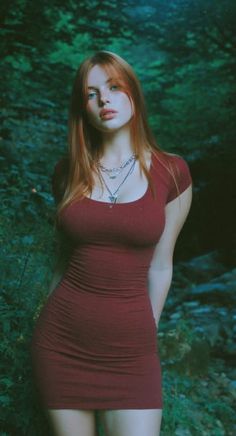 Woman with red hair in a tight red dress in a forest setting