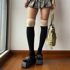 Person wearing a mini skirt, knee-high socks, and platform shoes indoors