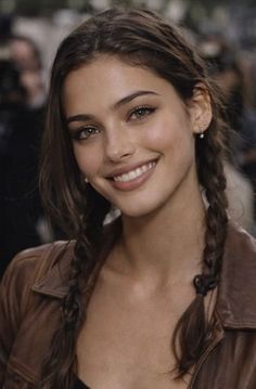 Woman with braided brown hair and a brown jacket smiling at the camera