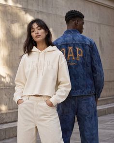 Two people in casual streetwear, a woman in a cream hoodie and a man in a denim jacket