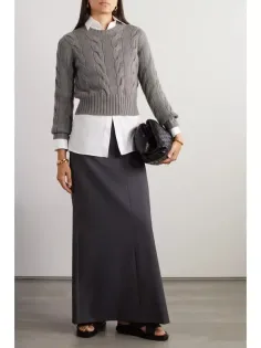 Woman in a gray cable knit sweater, white shirt, and long dark skirt