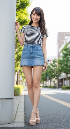 Woman in a striped shirt and denim skirt standing on a street