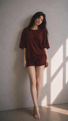 Woman in pajamas leaning against a wall with window shadows