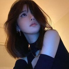 Woman with short dark hair wearing a black top and choker, looking up