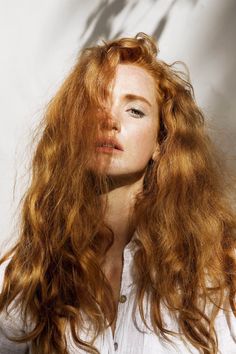 Woman with long red hair and freckles in a white shirt with dramatic lighting