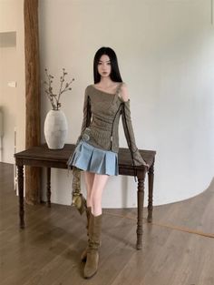Woman with long black hair wearing a pleated skirt and off-shoulder top indoors