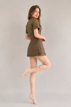 Woman in a brown leather dress and butterfly-patterned tights posing indoors