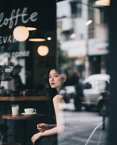Woman with long dark hair sitting in a cafe, looking over her shoulder