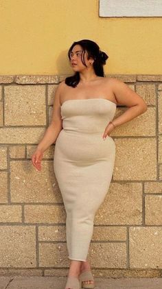Woman in a strapless dress posing against a stone wall