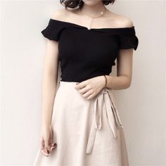 Woman in a black off-shoulder top and beige skirt with a pearl necklace
