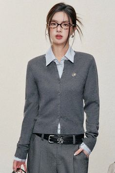 Woman in a gray cardigan, striped shirt, and glasses with hair in an updo