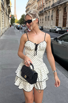 Woman in a polka dot dress and sunglasses on a street with the Eiffel Tower in the background