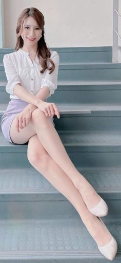 Woman in a white blouse and mini skirt sitting on stairs with crossed legs