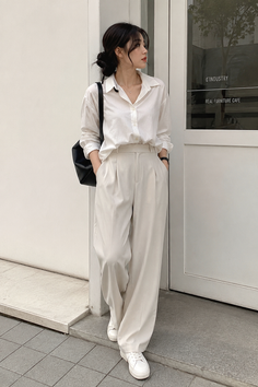 Woman in a white shirt and wide leg pants standing outdoors
