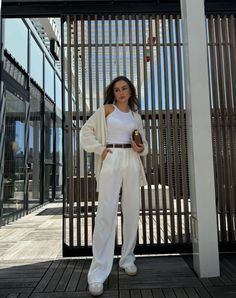 Woman in a white outfit with a cardigan and brown accessories outdoors
