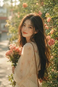 Woman with long dark hair holding pink roses in a floral dress outdoors