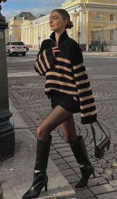 Woman in a striped sweater and black boots walking on a cobblestone street