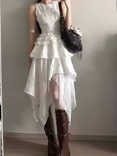Person in a white ruffled dress and brown boots with a shoulder bag