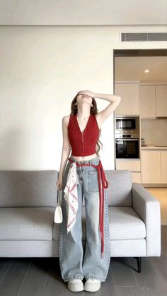 Woman in a red crop top and wide leg jeans posing indoors