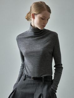 Woman in a grey turtleneck and trousers with her hair in an updo