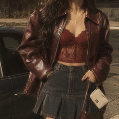 Woman in a red leather jacket and lace top with a denim skirt