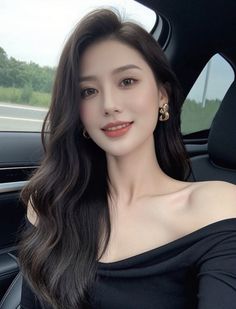 Woman with long dark hair wearing an off-shoulder top in a car