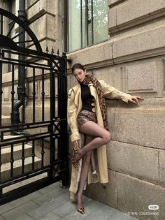Woman in a trench coat and leopard print outfit posing outdoors