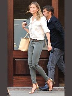 Woman in a white shirt and skinny jeans walking outdoors with a man