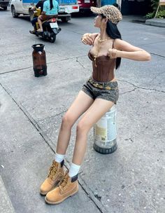 Woman in a brown corset and leopard print shorts sitting on a street