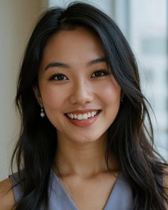 Woman with long black hair and pearl earrings smiling at the camera