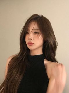 Woman with long brown hair wearing a black top, looking to the side