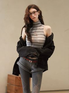 Woman with long hair and glasses wearing a striped top, denim jacket, shorts, and tights