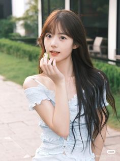 Young woman with long hair holding a green fruit outdoors