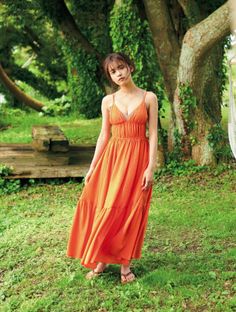 Woman in an orange dress standing on green grass outdoors