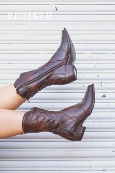 Pair of brown leather cowboy boots with embroidered design and zippers