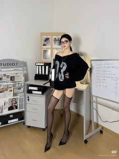 Woman in a black sweater, stockings, and high heels in an office setting