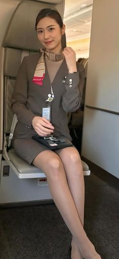 Woman in a flight attendant uniform sitting in an airplane cabin