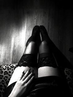Person wearing thigh high stockings with lace trim and long dark nails