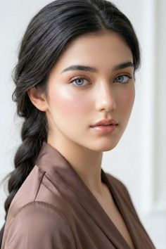 Woman with blue eyes and dark braided hair wearing a satin robe
