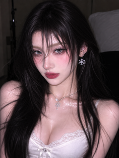 Woman with long dark hair and snowflake jewelry in a white lace-trimmed top