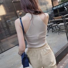 Woman with long hair wearing a sleeveless top and khaki pants, seen from behind