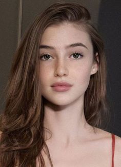 Close-up portrait of a young woman with long brown hair and green eyes