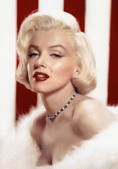 Woman with blonde hair and red lipstick wearing a necklace and white fur