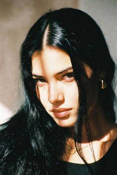 Woman with long black hair in dramatic lighting with shadows across her face