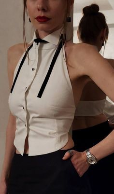 Woman in a white halter top and black pants with red lipstick and a watch