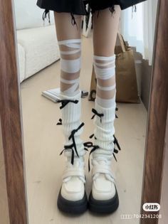 Person wearing white leg warmers with black bows and platform shoes