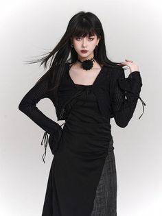 Woman with long black hair and dark makeup wearing a black dress and choker