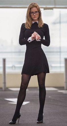 Woman in a black dress and glasses standing outdoors