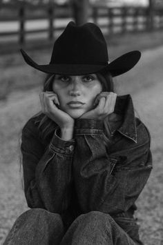 Woman in a cowboy hat and denim jacket, resting her chin on her hands